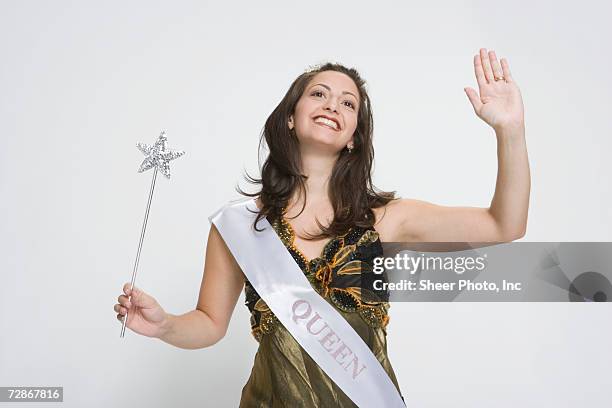 beauty queen waving hand, holding magic wand, smiling - schoonheidswedstijd stockfoto's en -beelden