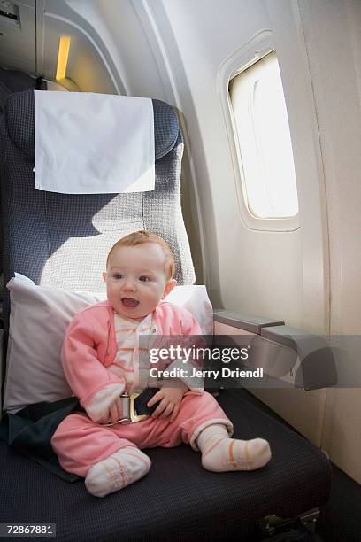 baby girl (6-9 months) sitting in airplane seat, smiling - 6 11 maanden stockfoto's en -beelden