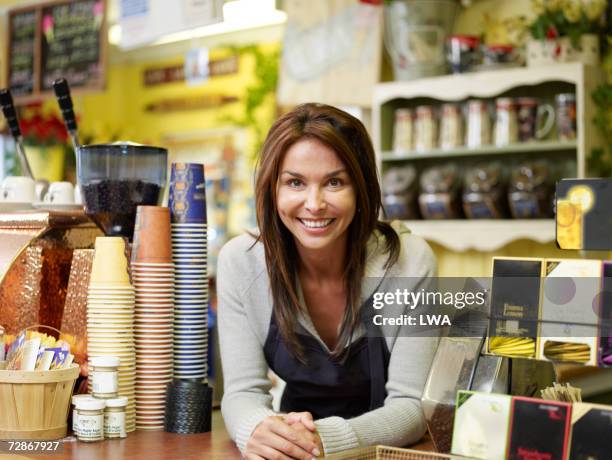 woman standing behind coffee shop counter, smiling, portrait - caft stock pictures, royalty-free photos & images