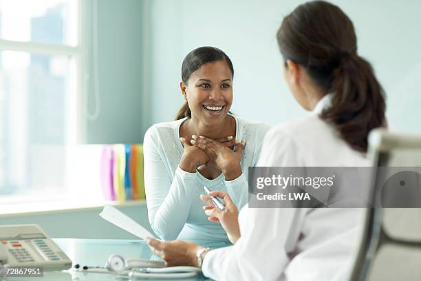 young woman talking to doctor, smiling - frau sorgen 45 jahre stock-fotos und bilder