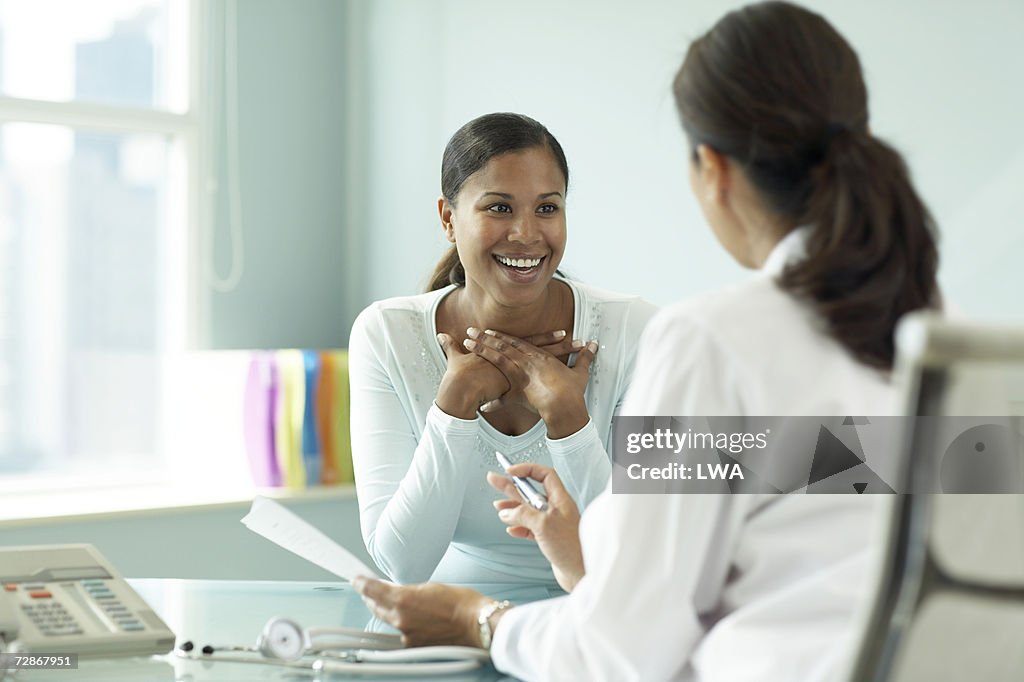 Young woman talking to doctor, smiling