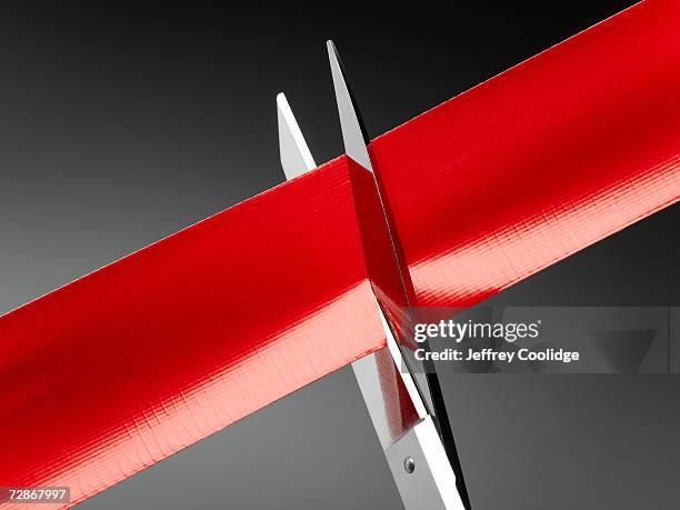 red tape being cut by scissors, close-up - burocrazia foto e immagini stock