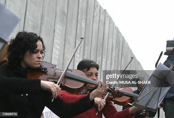 Spanish artist Cristina del Valle conducts an orchestra in front of the controversial separation barrier being built by Israel and said to be illegal...