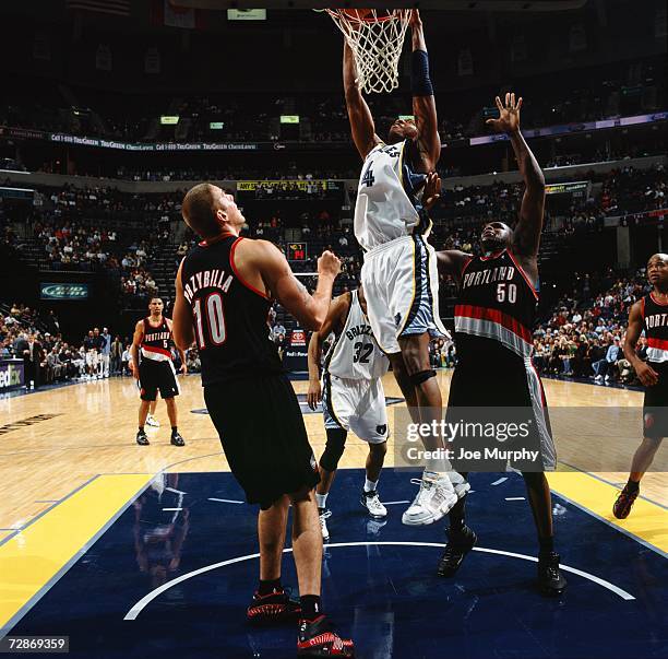 Stromile Swift of the Memphis Grizzlies takes the ball to the basket against Zach Randolph and Joel Przybilla of the Portland Trail Blazers during a...