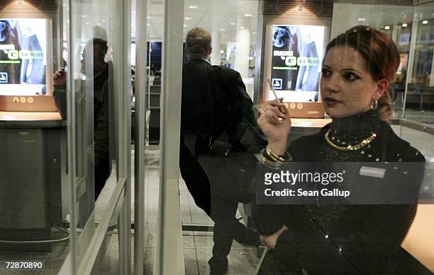 Young woman and other travelers smoke in a special smoker's cabin at Munich Airport December 22, 2006 in Munich, Germany. German lawmakers are...