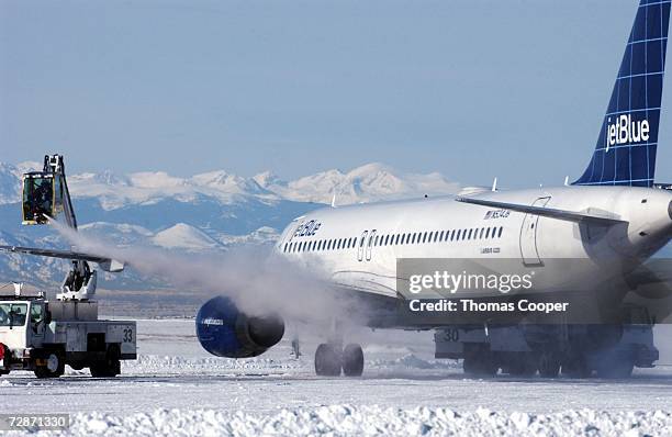 De-Icing crews remove snow and ice from a plane that has been grounded due to a recent blizzard at Denver International Airport December 22, 2006 in...