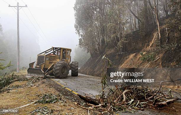 Workers clear the blocked road to Mount Buller in misty conditions after rain overnight dampened the massive bushfires at Sawmill Settlement as a...