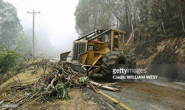 Workers clear the blocked road to Mount Buller in misty conditions after rain overnight dampened the massive bushfires at Sawmill Settlement as a...