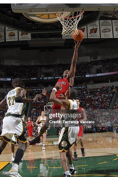 Fred Jones of the Toronto Raptors goes to the basket against Earl Watson and Johan Petro of the Seattle SuperSonics at the Key Arena December 23,...