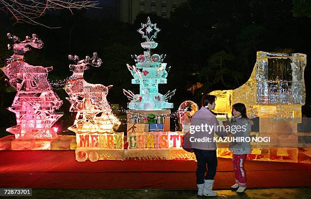People pose for a photographs next to ice sculptures a garden of Tokyo's Takanawa Prince Hotel, 24 December 2005 as part of its annual year-end...