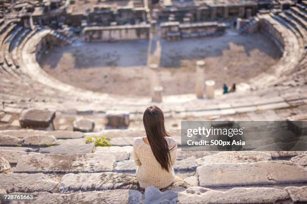 lone woman sitting in ephesus theatre, selcuk, izmir province, turkey - ephesus foto e immagini stock