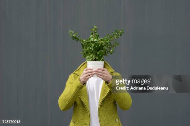 Close-Up Of Person With Potted Plant Against Grey Background