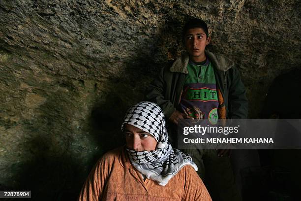 Palestinian mother Bahija Bani Jaber stands with her 14-year-old son Yussef in their home, a cave, where her and her family live during the winter...