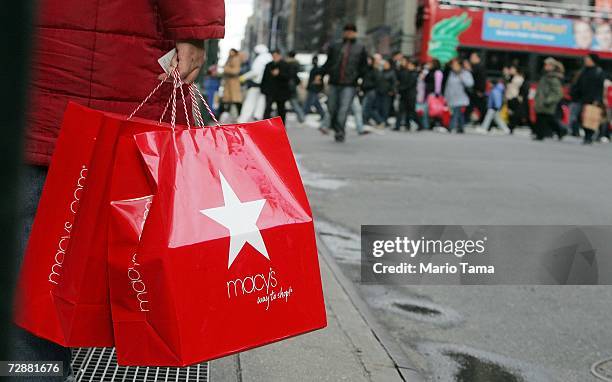 Post-Christmas shopper holds Macy's bags as other shoppers cross Seventh Avenue December 27, 2006 in New York City. Retailers are hoping that...