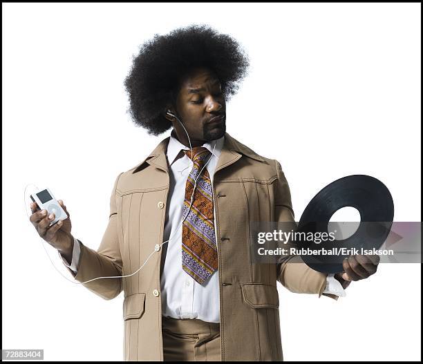 man with an afro in beige suit listening to mp3 player - modischer anzug stock-fotos und bilder