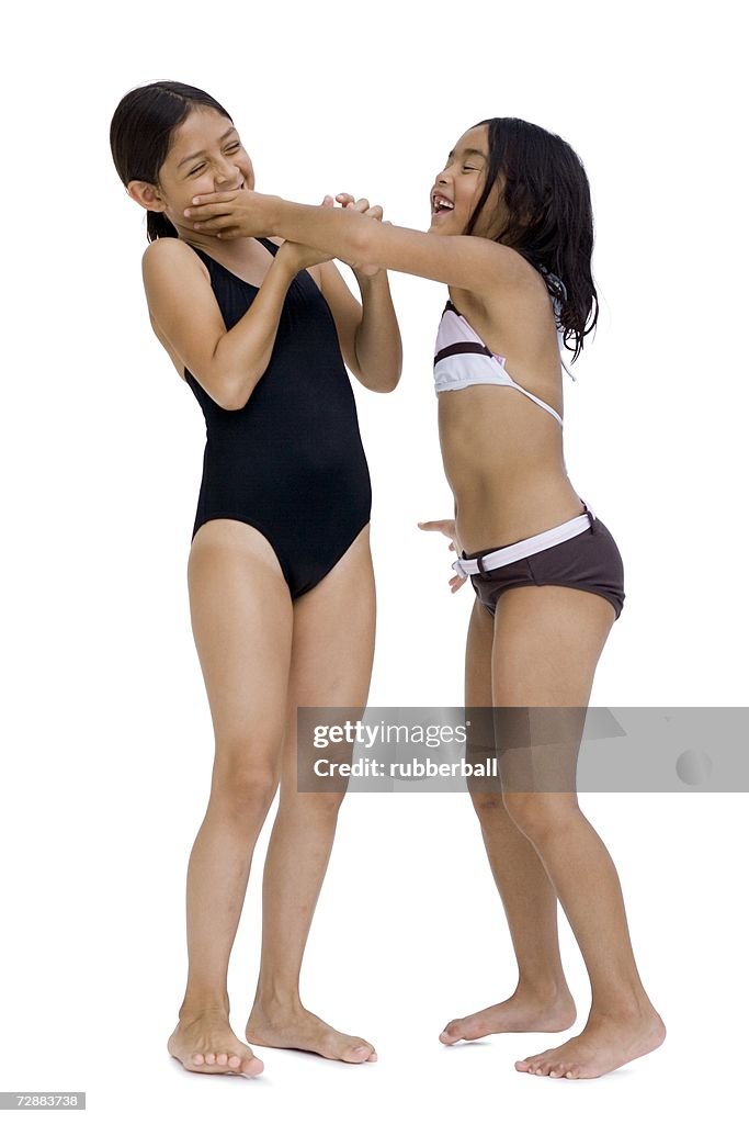 Two girls in bathing suits playfighting