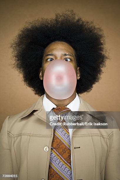 man with an afro in beige suit blowing a bubble - gencive photos et images de collection
