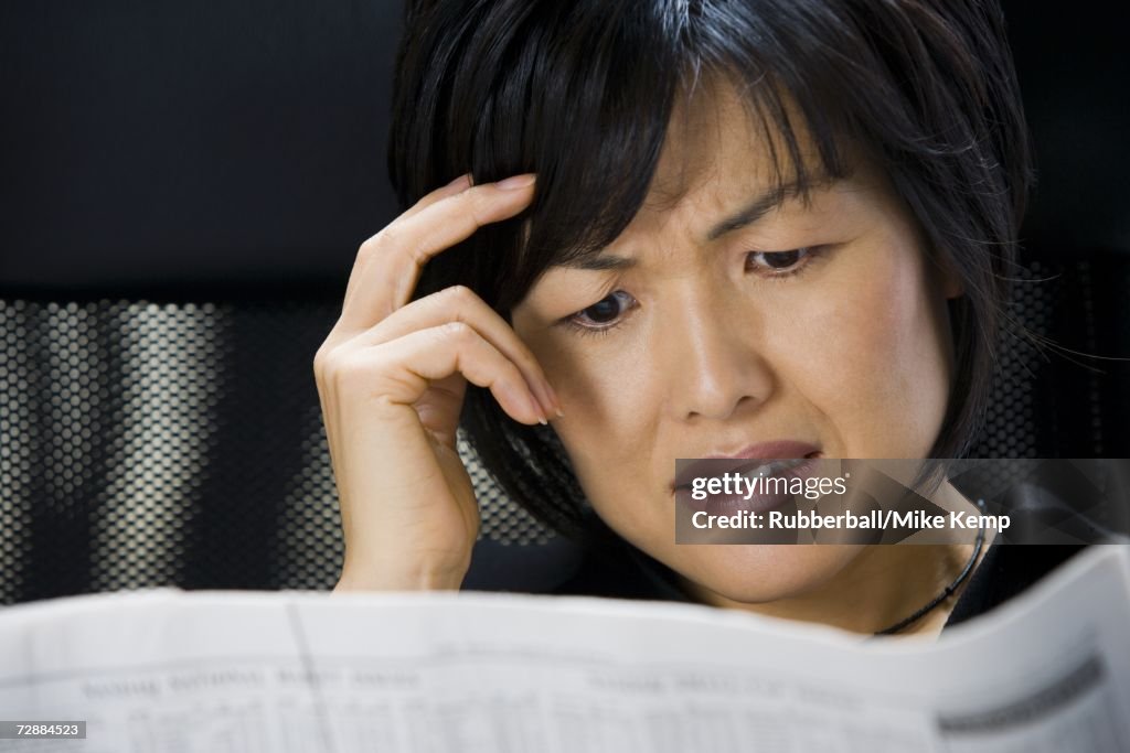 Woman reading financial pages of newspaper
