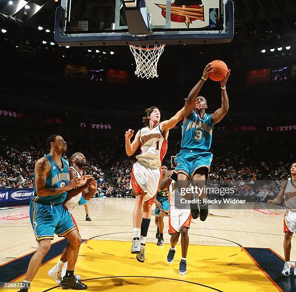 Chris Paul of the New Orleans/Oklahoma City Hornets takes the ball to the basket against Troy Murphy of the Golden State Warriors during a game at...