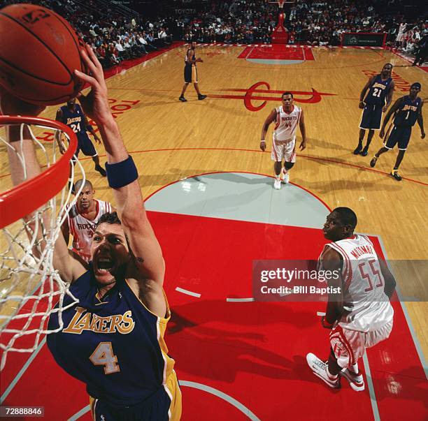 Luke Walton of the Los Angeles Lakers takes the ball to the basket past Dikembe Mutombo of the Houston Rockets during game at Toyota Center on...