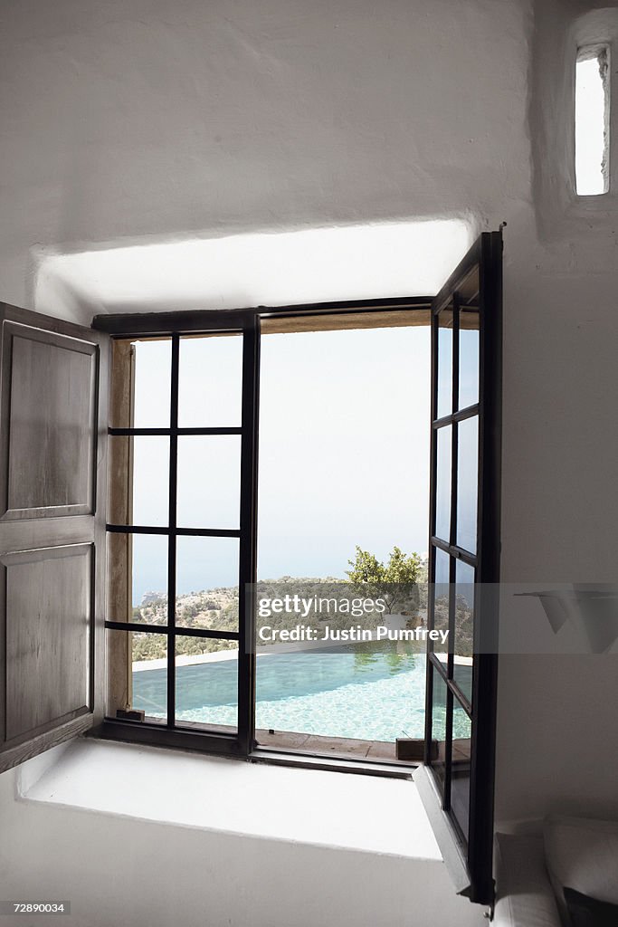 View of empty swimming pool through open window