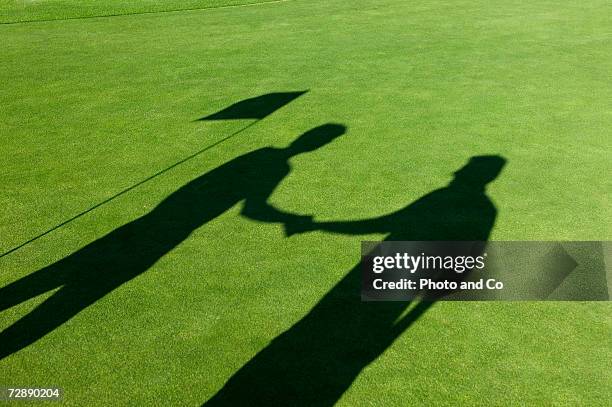 shadows of two male golfers shaking hands on golf course - golf fotografías e imágenes de stock