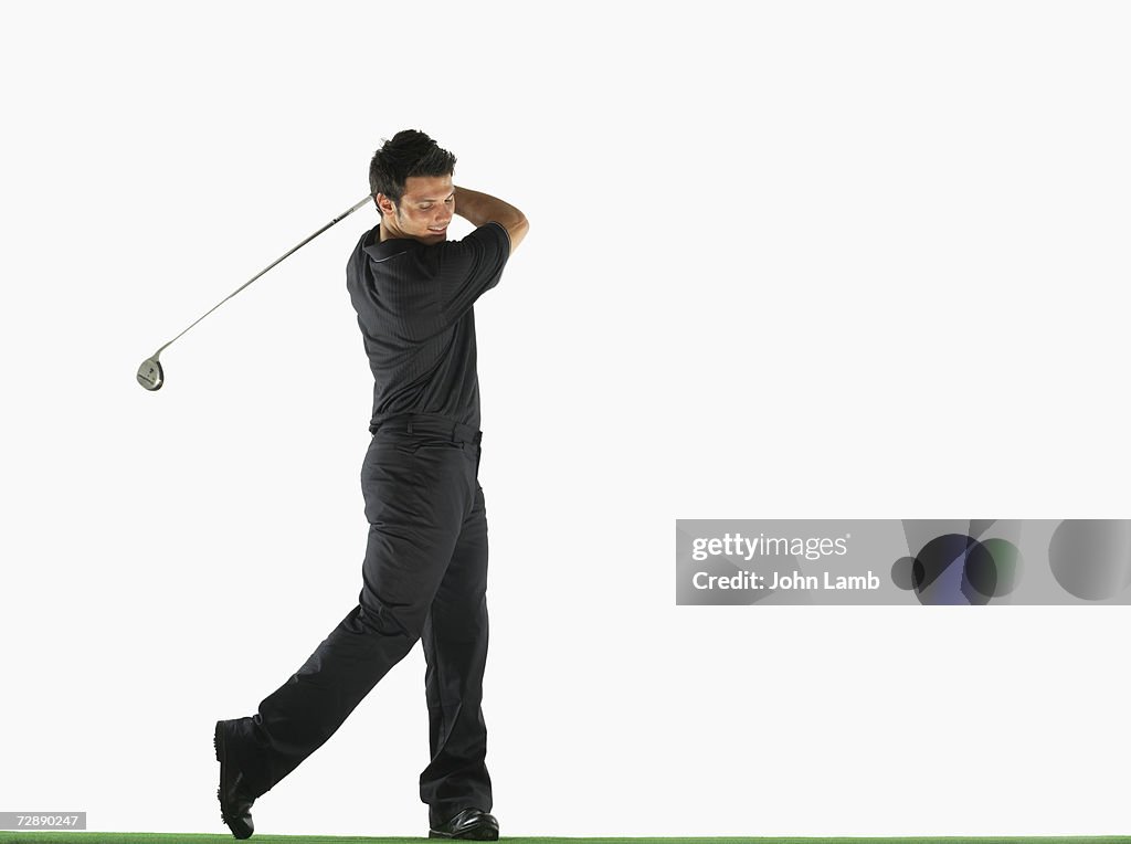 Male golfer swinging golf club