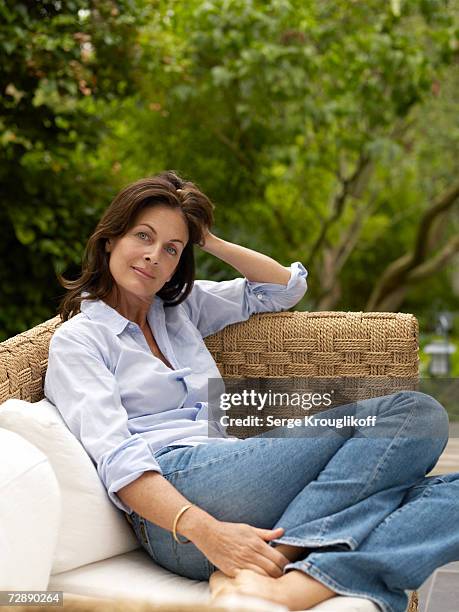 mature woman relaxing on veranda - jeans barefoot stock pictures, royalty-free photos & images