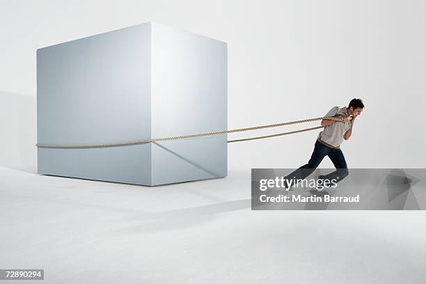 man pulling giant box with rope - tirar de fotografías e imágenes de stock