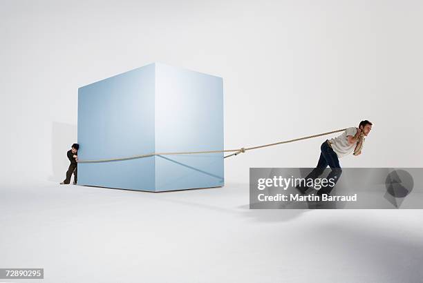 two men moving giant box with rope - pushing stock pictures, royalty-free photos & images