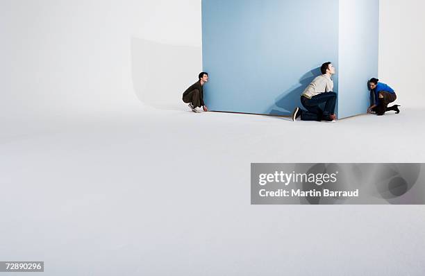 woman struggling to lift giant box with two men - confused white background stock-fotos und bilder