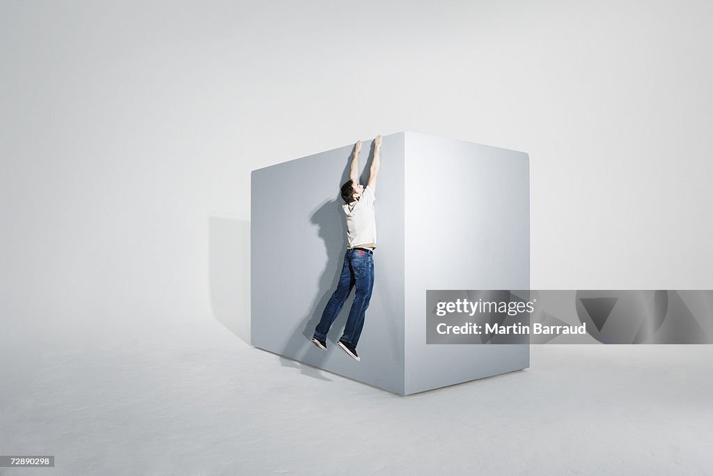 Man assisting colleague climbing on giant box