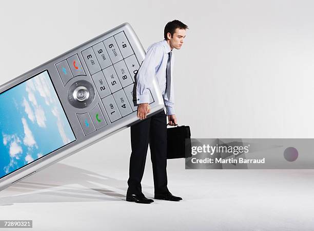 businessman dragging giant model mobile phone - size 30 stock pictures, royalty-free photos & images