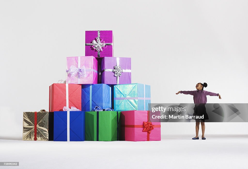 Girl (6-7) standing by stack of giant presents