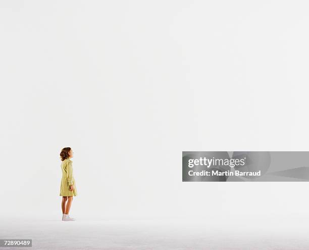 girl (8-9) standing in empty white room - girl side view stockfoto's en -beelden