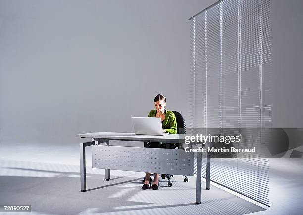 young businesswoman sitting at desk, using laptop - secretary stock pictures, royalty-free photos & images