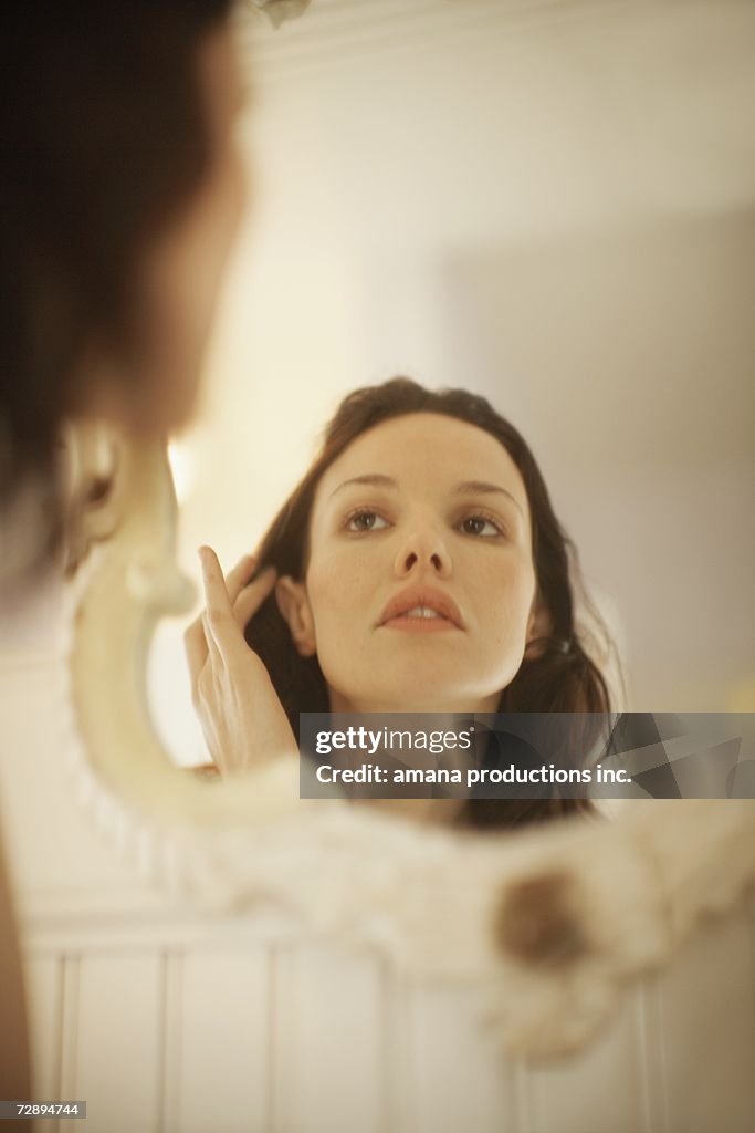 Woman fixing hair in front of mirror