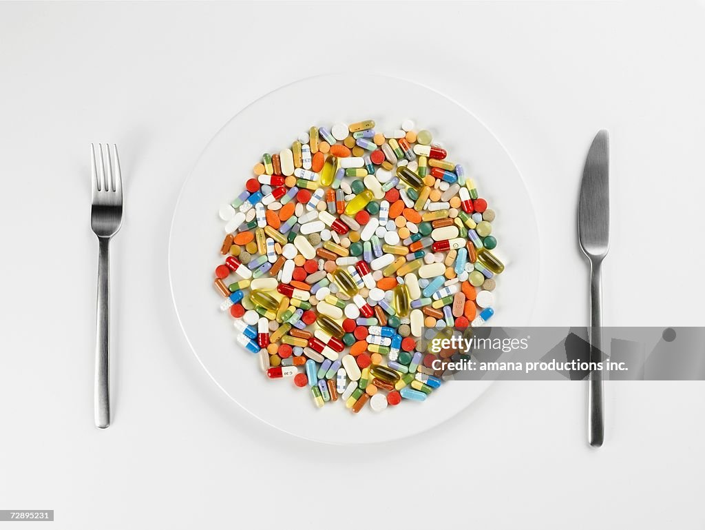 Mixed pills on white plate (close-up, directly above)