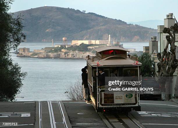 San Francisco, UNITED STATES: A cable car moves down to Fisherman's Wharf before Alcatraz Island in San Francisco, 22 December 2007. The City and...