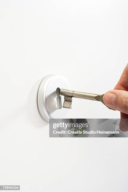 hand putting key in keyhole, close-up - key hole stock pictures, royalty-free photos & images