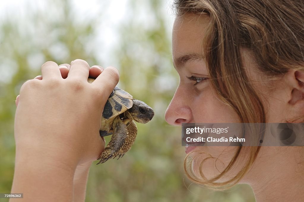 Teenage girl holding turtle, close-up