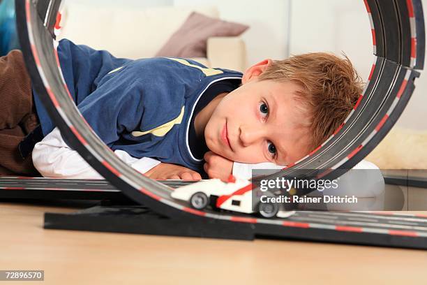 boy (6-7) playing with toy racetrack, close-up - modellauto-rennbahn stock-fotos und bilder