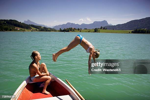 young girl in rowing boat with friend, jumping into lake - girl looking down stock pictures, royalty-free photos & images