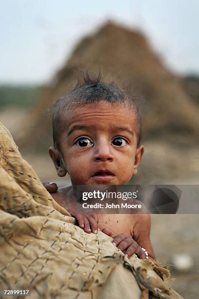 Malnourished one-year-old Imdad Gul peers from over his mother's shoulder at a camp on December 28, 2006 in Jafarabad, Pakistan. A UNICEF report says...