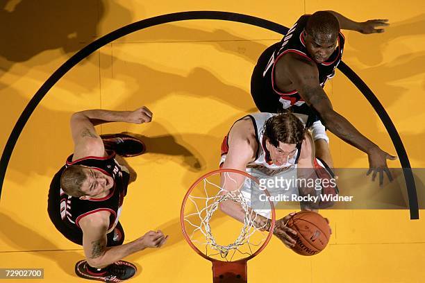 Troy Murphy of the Golden State Warriors takes the ball to the basket against Joel Przybilla and Zach Randolph of the Portland Trail Blazers during a...