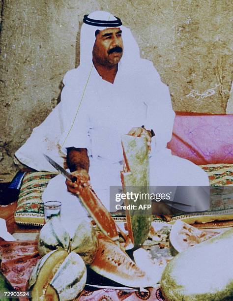 This undated file photograph shows Iraqi leader Saddam Hussein wearing traditional Arabian robes as he cuts a watermelon at an undisclosed location....