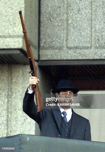 : This 31 December 2000 file photograph shows Iraqi President Saddam Hussein holding up his rifle during a military parade at Nasr Square in Baghdad....