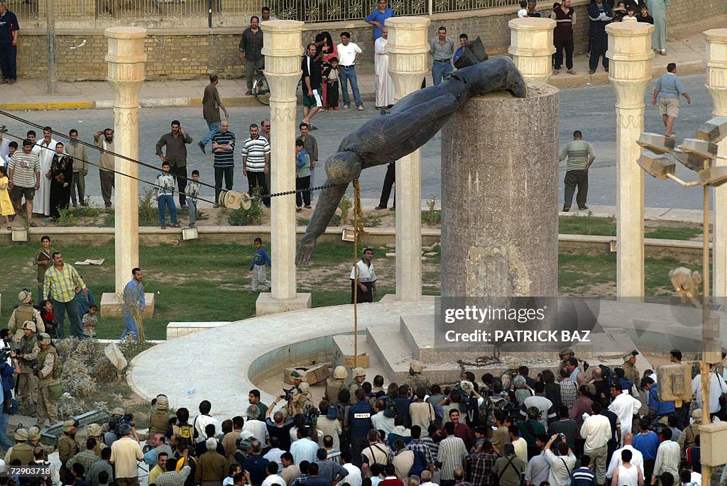 (FILES) Iraqis watch a statue of Iraqi P