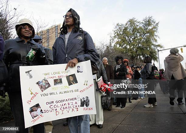 Augusta, UNITED STATES: Brenda Wright holds a handwritten sign as she waits in a line to view the body of soul singer James Brown, 30 December 2006,...