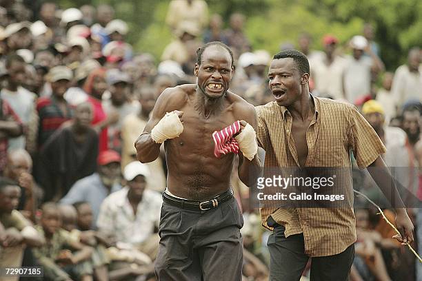 Khwthelani Ralukake celebrates while Mmbulawru Kota Mmbudzeni looks on during a traditional fist fighting match on December 29, 2006 in Tshaulu...